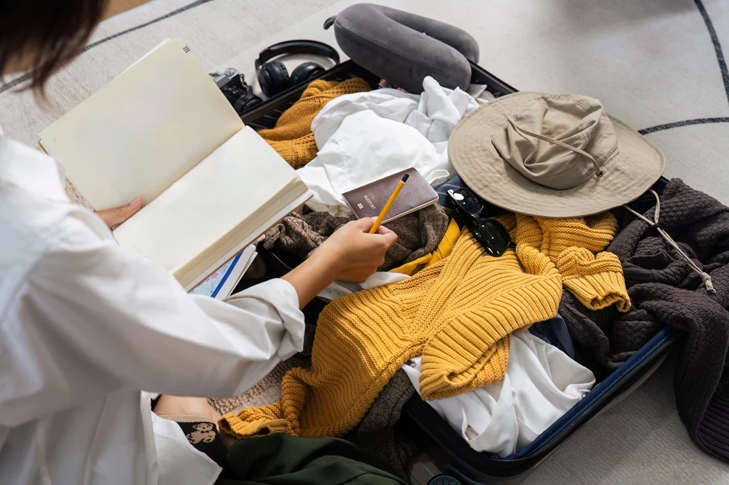 Person packing a suitcase with travel essentials and clothing