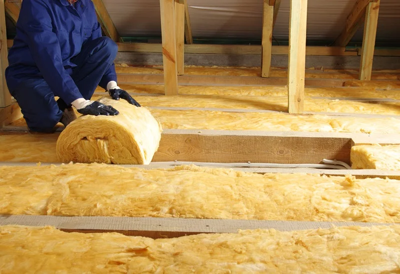 Worker installing eco-friendly insulation made from recycled materials in an attic, enhancing energy efficiency and sustainability.